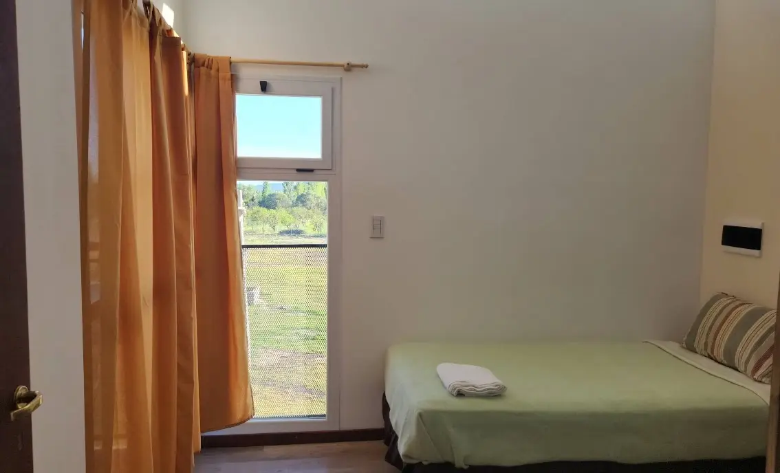 Dormitorio con cama simple y gran ventanal
